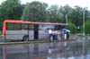in attesa di salire sul bus, in coda per il biglietto, alcuni viaggiatori attendono ligi il loro turno sotto l'acqua
